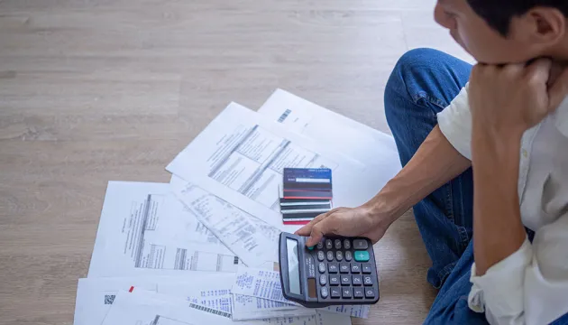 man sitting on floor with credit card bills