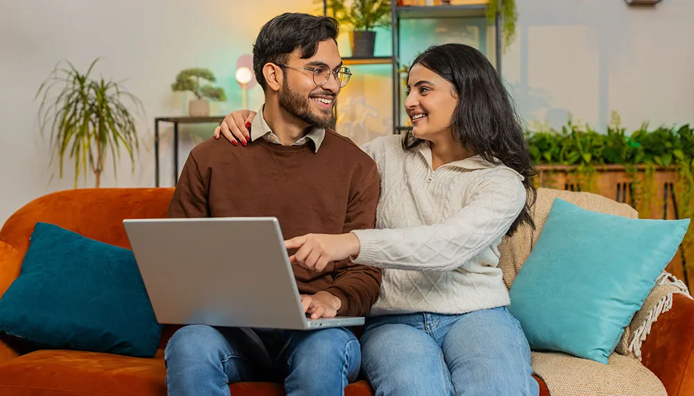 couple smiling while using computer